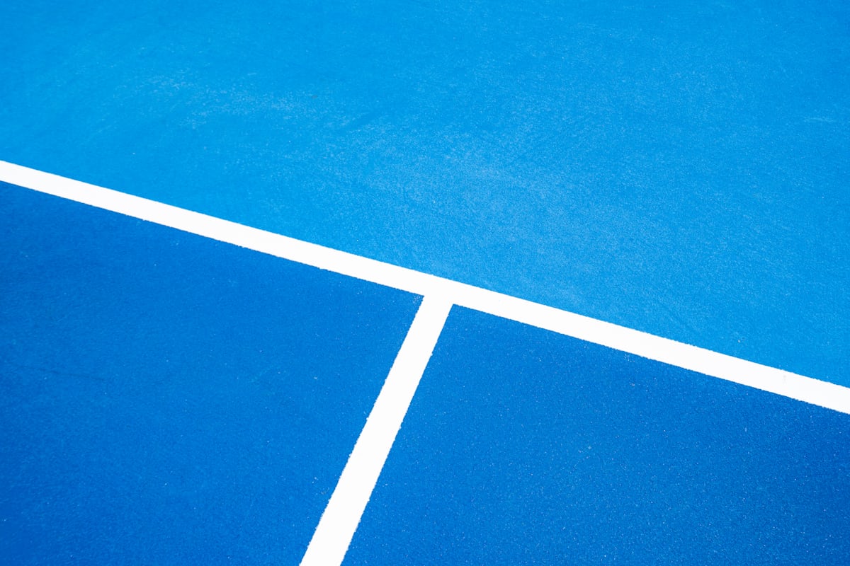 Close-up of crisp white sideline and baseline markings painted on a blue pickleball court surface