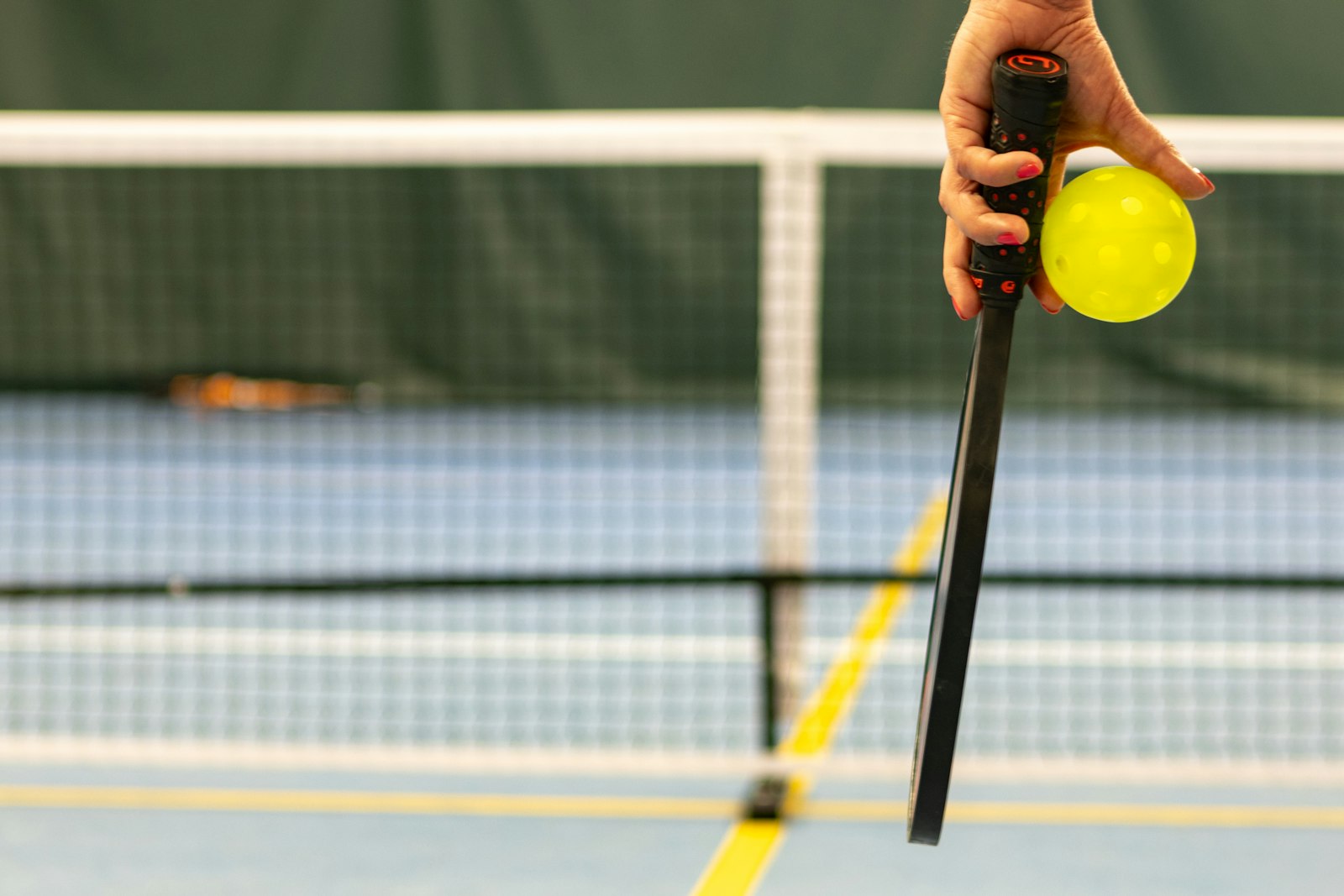 Close-up of a hand wrapped around a pickleball paddle handle